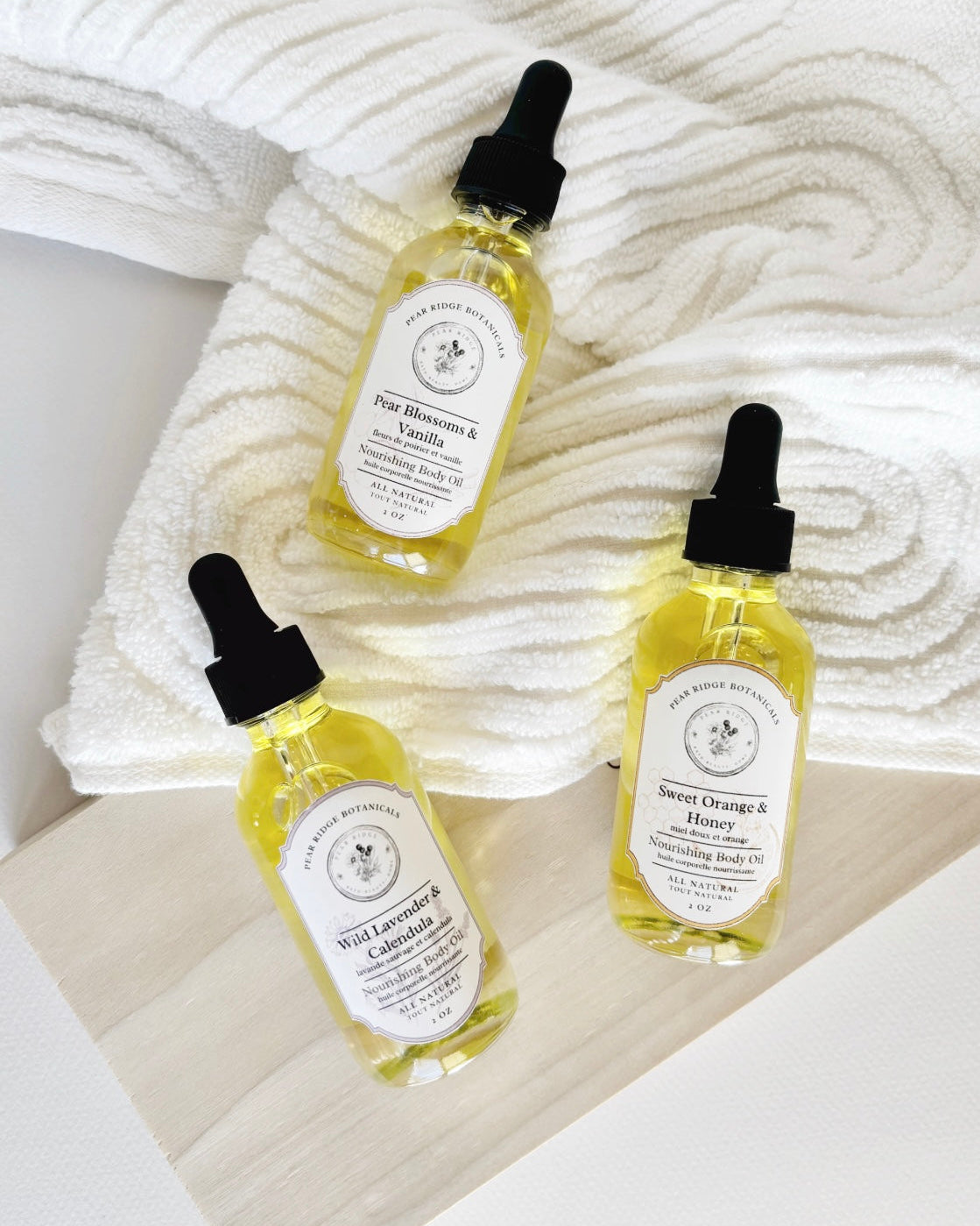Three bottles of natural skincare products with droppers on a textured white surface.